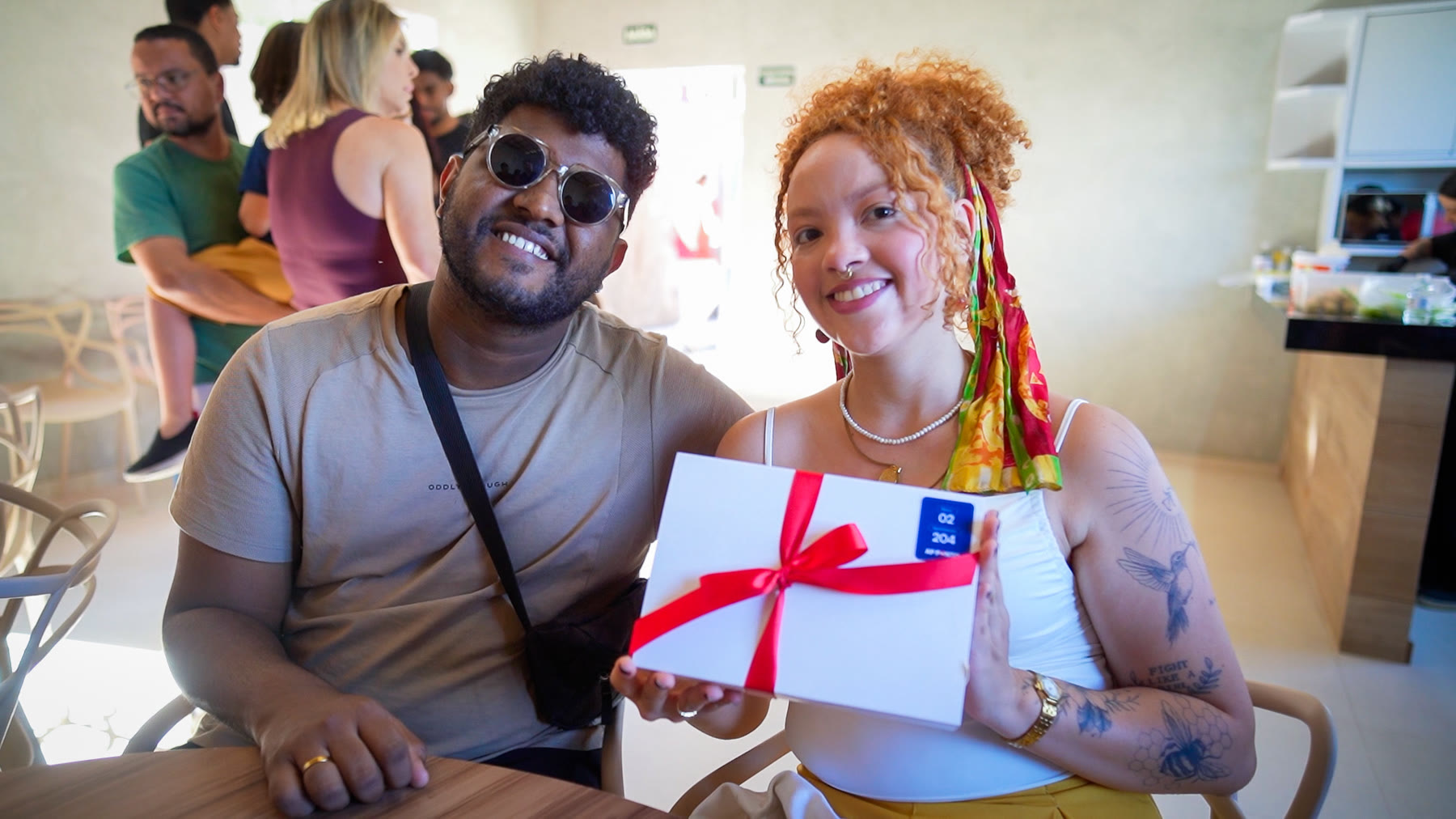 Casal sorri com o presente recebido na entrega do apartamento