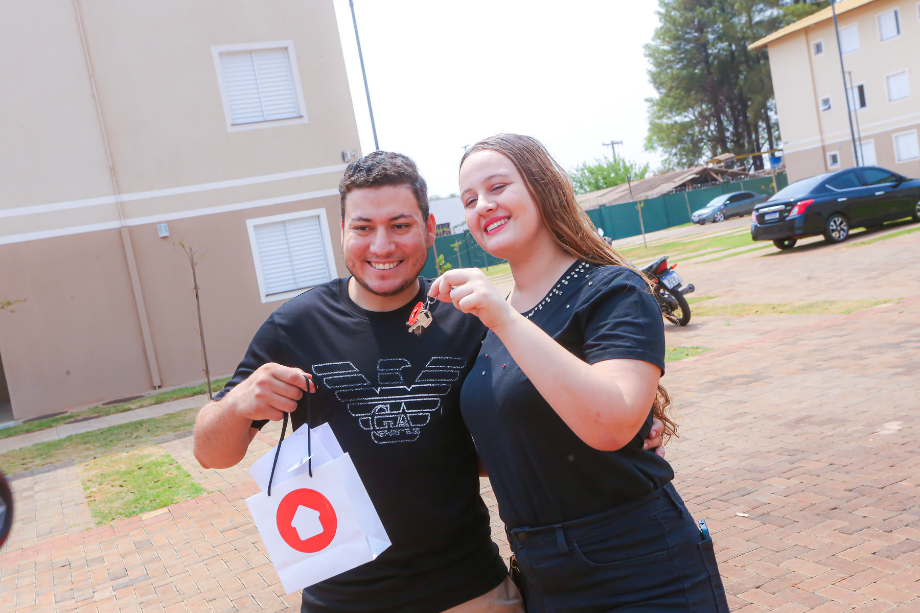 Casal celebra com as chaves diante do empreendimento entregue